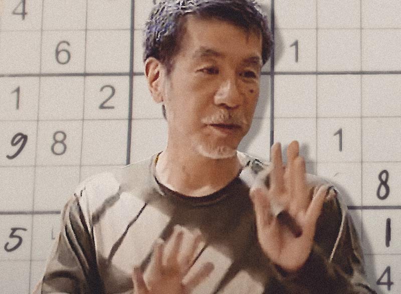 Maki Kaji, der Vater des Sudoku, vor einem Sudoku-Gitter